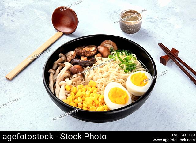 Ramen. Soba noodles with boiled eggs, mushrooms, and vegetables, with sake, traditional wooden spoon, and chopsticks