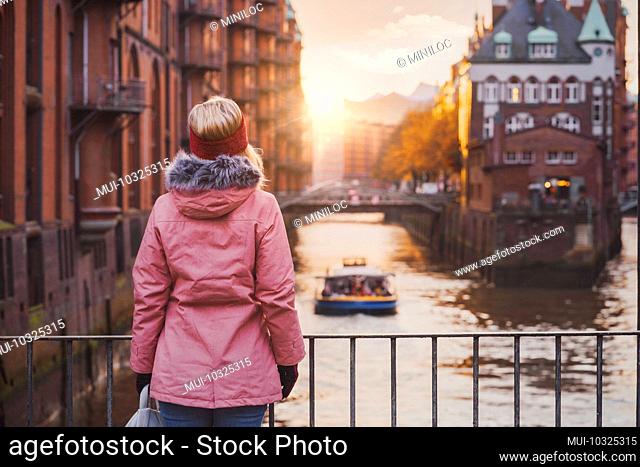 Back view of a woman with a view of the historic warehouse district in Hamburg in the warm light of sunset, Germany, Europe