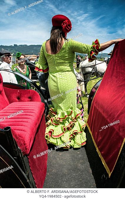 Women dressed in ruffled dress, poses for his friends before leaving the carriage. Andalusian Pilgrimage. Villaviciosa, Asturias, Spain