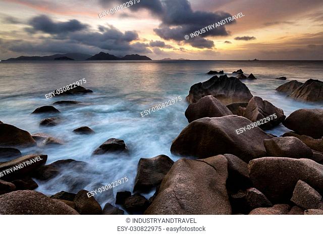 Sunset long exposure with view to Praslin from La Digue, Seychelles with granite rocks in the foreground