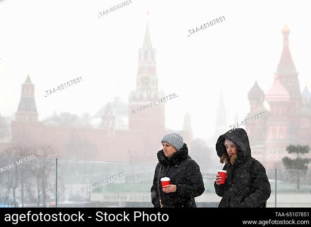 RUSSIA, MOSCOW - NOVEMBER 23, 2023: People walk in Zaryadye Park during a snowfall with the Moscow Kremlin's Spasskaya Tower and St Basil's Cathedral in the...