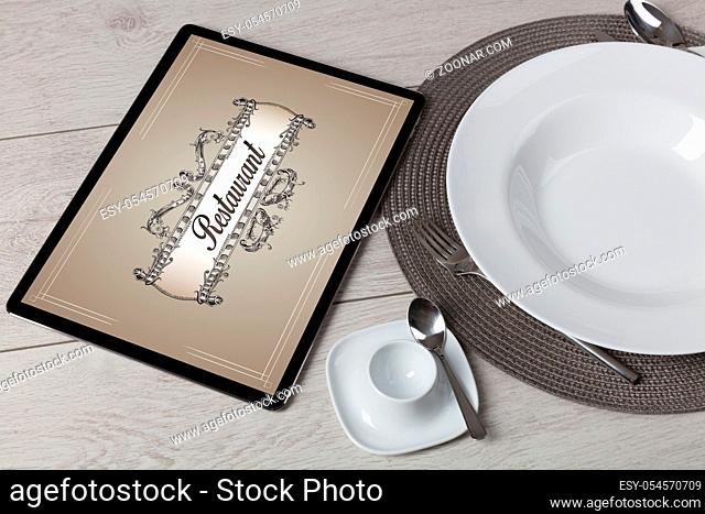 Tablet with stylish restaurant logo and laid table
