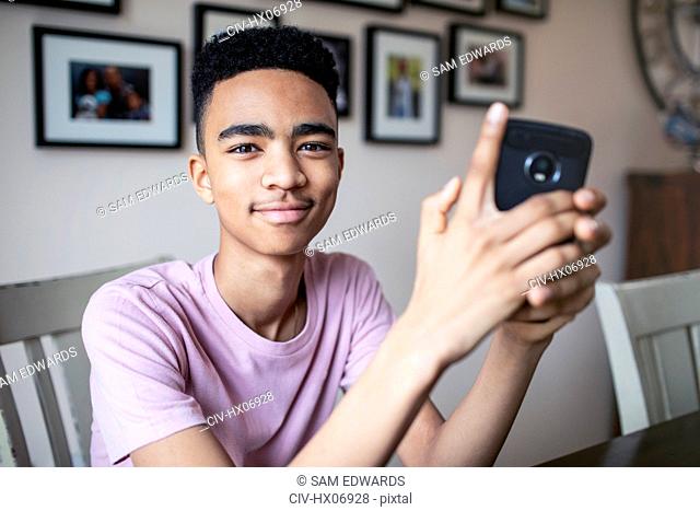 Portrait confident teenage boy using smart phone