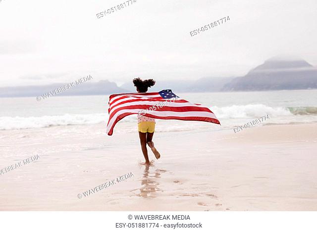 Girl running with American flag on the beach