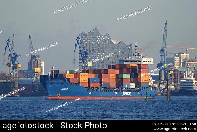 PRODUCTION - 03 January 2023, Hamburg: A small container ship leaves a container terminal in the port. The Port of Hamburg on the Elbe is a universal port for...