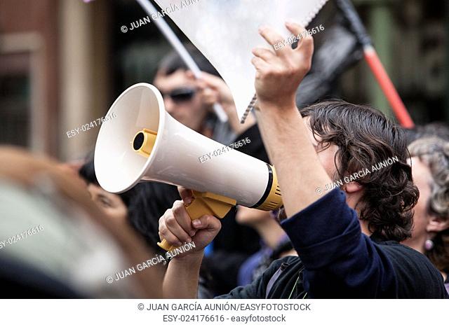 Unidentified young demostrator with megaphone and notebook protesting against austerity cuts