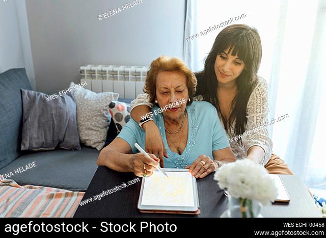 Smiling woman with grandmother using tablet PC at home