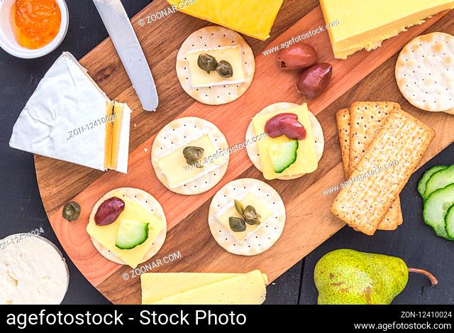 Cheese board with assorted cheese, and crackers on wooden board - top view photo