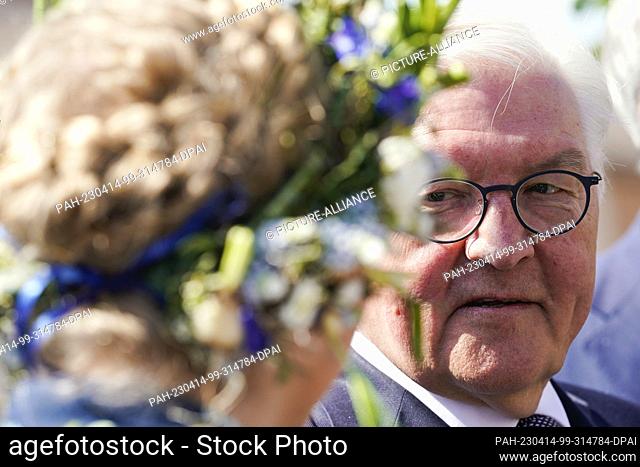 14 April 2023, Baden-Württemberg, Mannheim: Federal President Frank-Walter Steinmeier stands next to a woman with a wreath of flowers in her hair at the start...