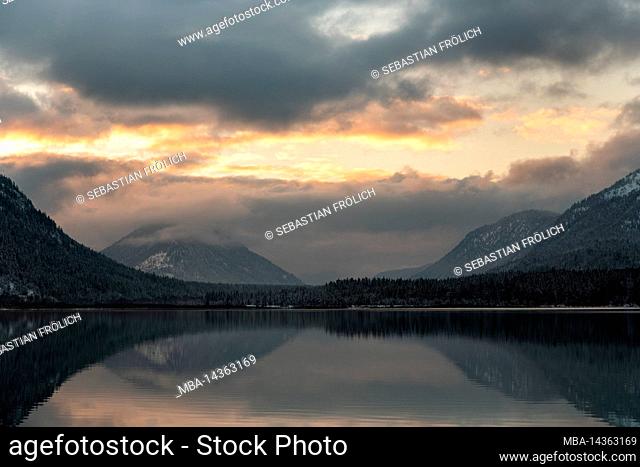 Sunset at Sylvenstein reservoir in Bavarian Alps in winter with snow and thick clouds