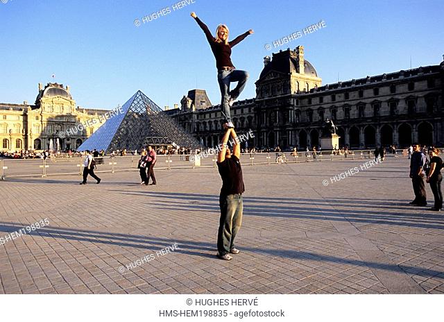 France, Paris, acrobats tourists in front of Louvre Museum