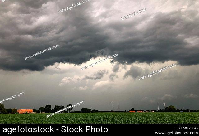 Threatening dark rainy clouds are covering a rural landscape, showing the Overcast and gloomy sky above the countryside creating a beautiful and impressive...