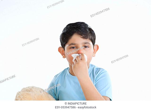 Portrait of little boy with tissue over mouth