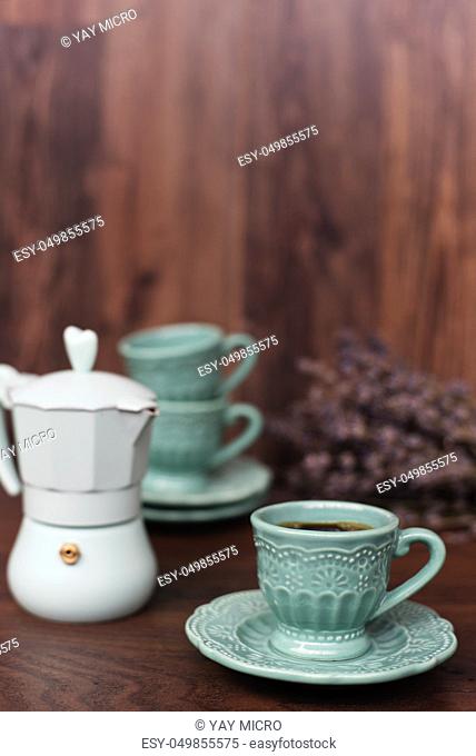 Cup of coffee and Italian coffee maker in blue, scent of lavender. Dark wooden background
