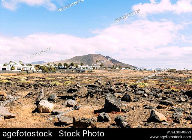 Spain, Canary Islands, Lanzarote, Rocky landscape with Montana Roja volcano in background