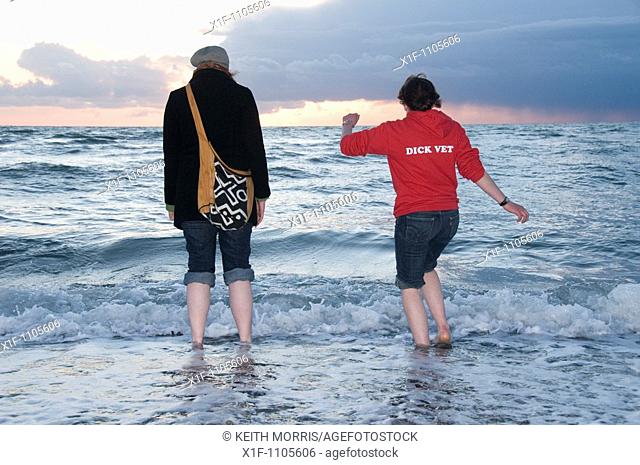 Two girls paddling in the sea at dusk students at Aberystwyth University - Cardigan Bay, Wales UK
