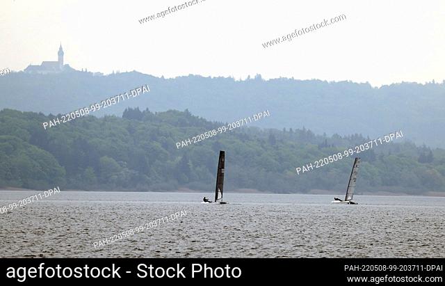 08 May 2022, Bavaria, Schondorf: Catamarans sail across the Ammersee under cloudy skies in front of Andechs Monastery. Photo: Karl-Josef Hildenbrand/dpa