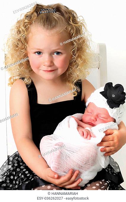 Beautiful blond girl, holding her newborn baby sister
