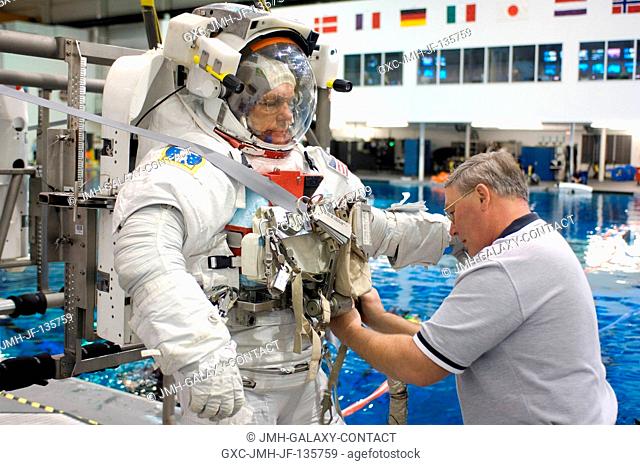 European Space Agency (ESA) astronaut Hans Schlegel, STS-122 mission specialist, dons a training version of the Extravehicular Mobility Unit (EMU) spacesuit...