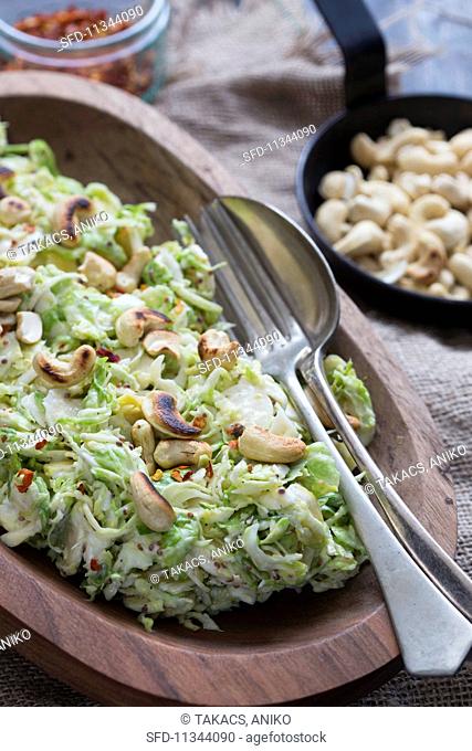 Brussels sprouts salad with roasted cashew nuts in a wooden bowl