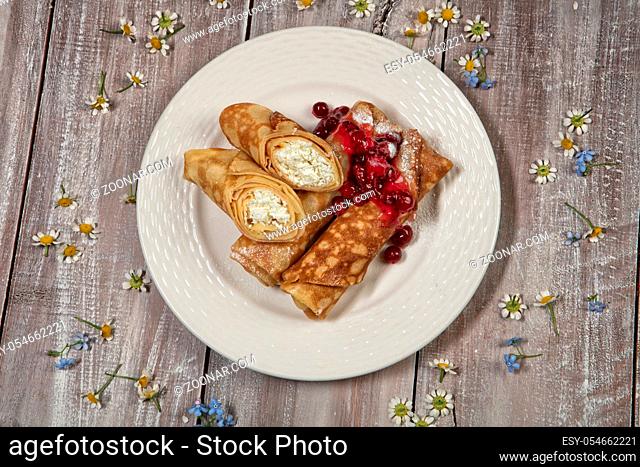 Plate with pancakes with meat and cup of tea on an old wooden background