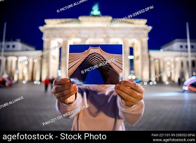 PRODUCTION - 27 October 2022, Berlin: Asadeh (name changed) holds a postcard with an image of the Freedom Tower (Azadi) of Tehran into the camera in front of...
