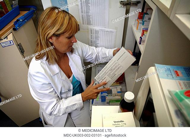 A female pharmacist reads the information label on the side of a mediction packet