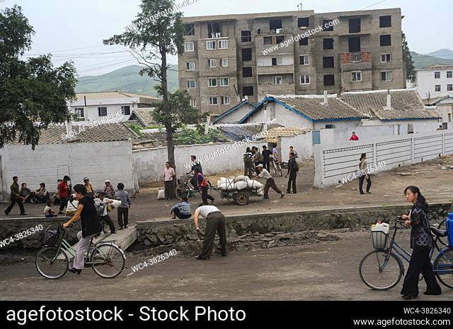 Wonsan, North Korea, Asia - An everyday scene near Wonsan depicts locals on a street with typical residential buildings in the backdrop