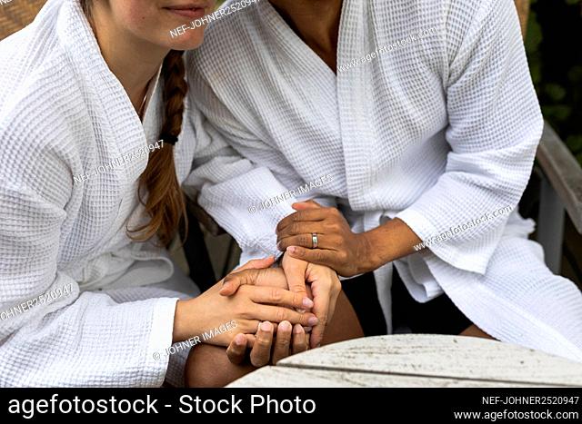 Close-up of couple in bathrobes holding hands