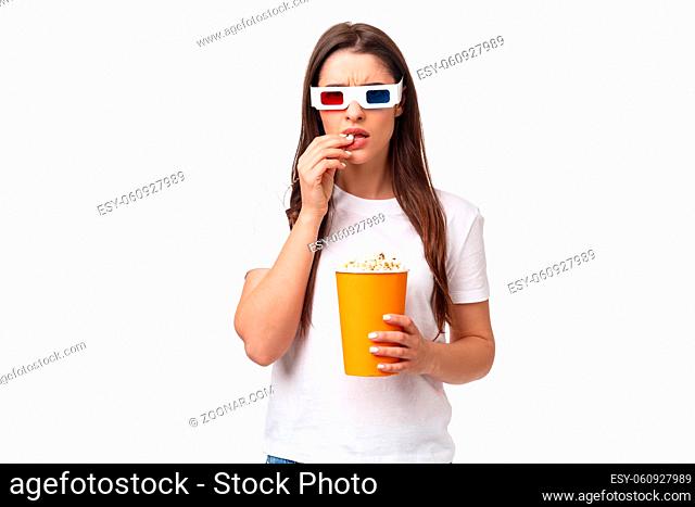 Entertainment, fun and holidays concept. Waist-up portrait of serious-looking focused young woman watching intense scene in movie, frowning and eating popcorn