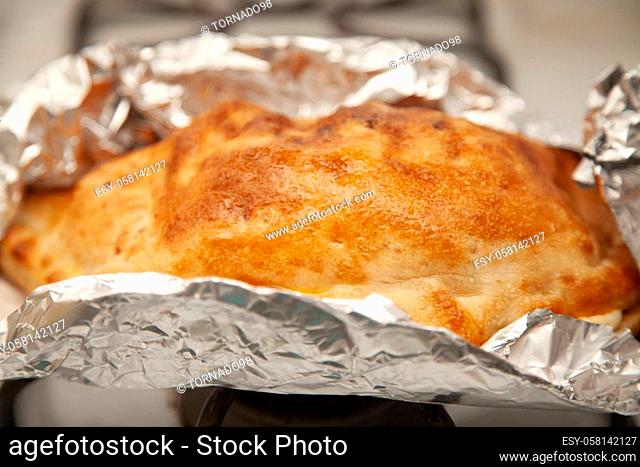 Glazed outter bread of a fresh calzone on foil