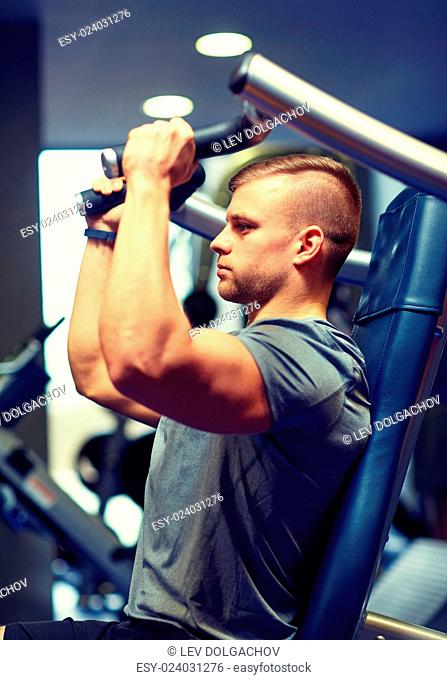 sport, fitness, bodybuilding, lifestyle and people concept - man exercising and flexing muscles on gym machine