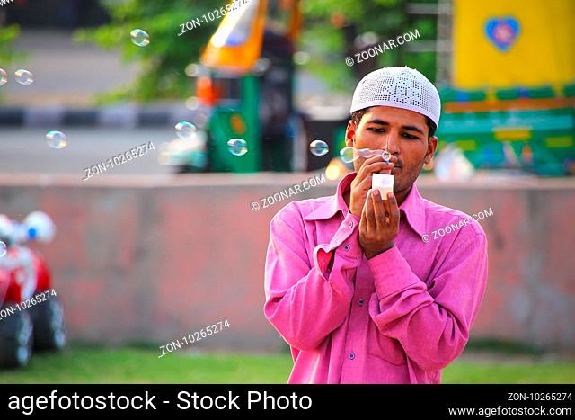 Local man making soap bubbles at Man Sagar Lake waterfront in Jaipur, India. Jaipur is the capital and the largest city of Rajasthan