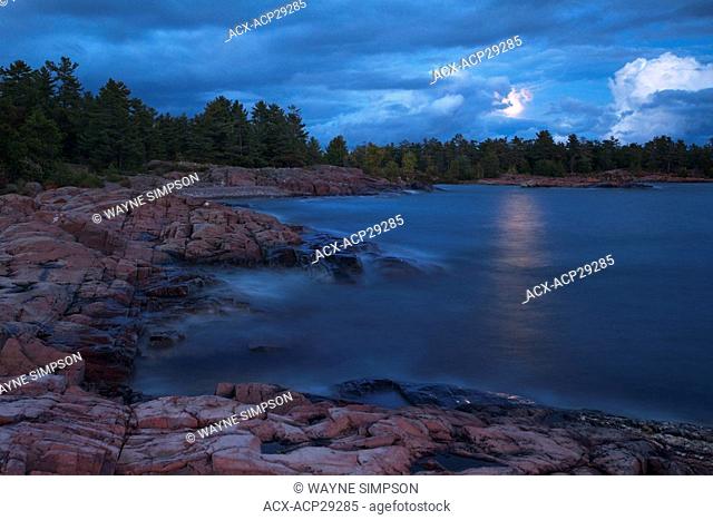 A full moon is unveiled as clouds pass over Georgian Bay in Killarney Provincial Park in Northern Ontario