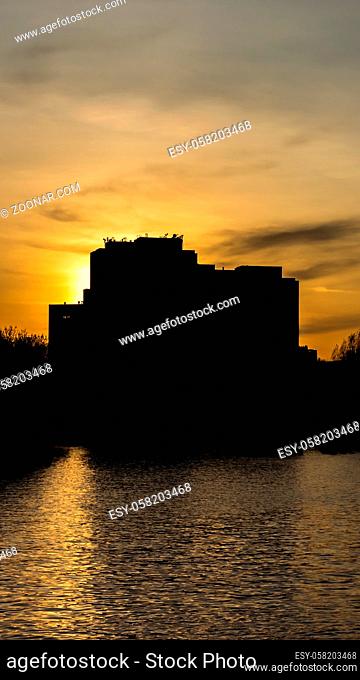Silhouette of an apartment building with back light in Berlin in the Spree in the foreground
