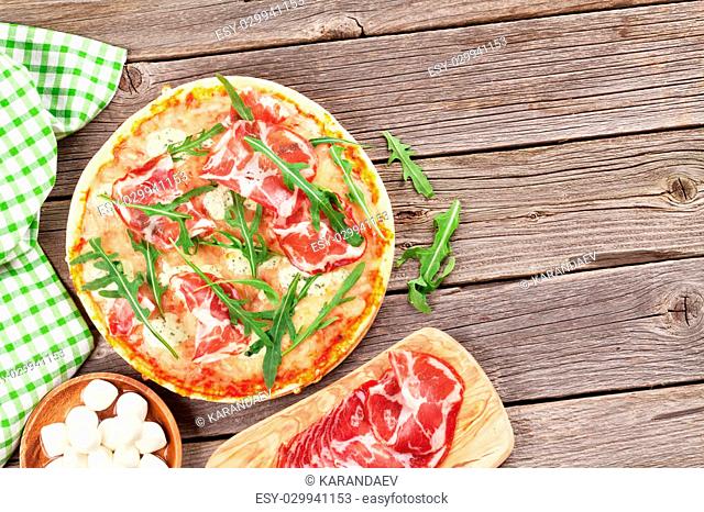 Pizza with prosciutto and mozzarella on wooden table. Top view with copy space