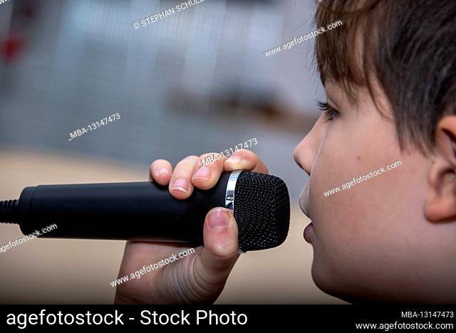 Boy sings, boy with microphone, close-up