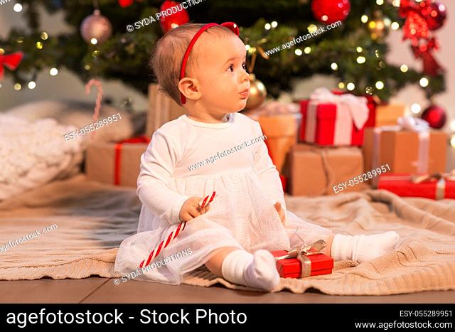 baby girl at christmas tree with gifts at home