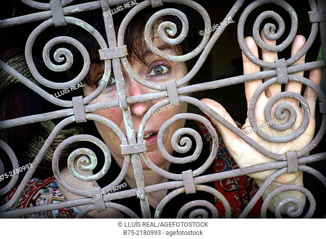 Young woman looking through a fence of a window in the Medina of Fez, Morocco, Africa