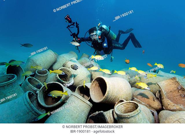 Diver with underwater camera looking at amphoras and fishes, Makadi Bay, Hurghada, Egypt, Red Sea, Africa