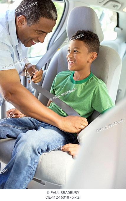 Grandfather fastening grandsonÍs seat belt in back seat of car