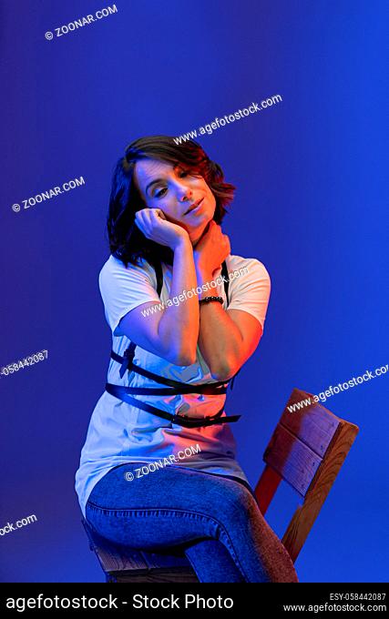 Brunette woman posing in Studio isolated on blue background. Young model illuminated with pink neon light