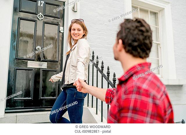 Young woman and boyfriend at front door, Kings Road, London, UK