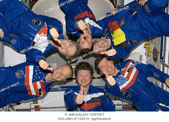 Expedition 20 crew members give a thumbs-up signal as they pose in star-burst formation for an in-flight portrait in the Harmony node of the International Space...