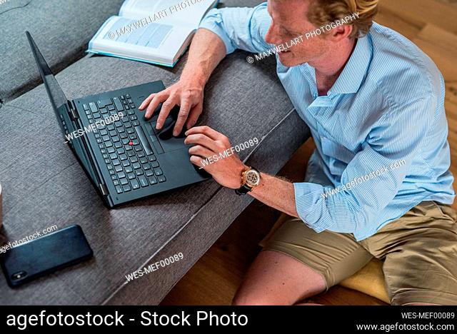 Male freelancer working on laptop in living room