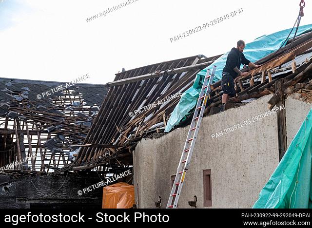 22 September 2023, Rhineland-Palatinate, Nusbaum: Carpenter Dennis Kinnen works on the destroyed roof of a farm building that was damaged by a tornado the day...