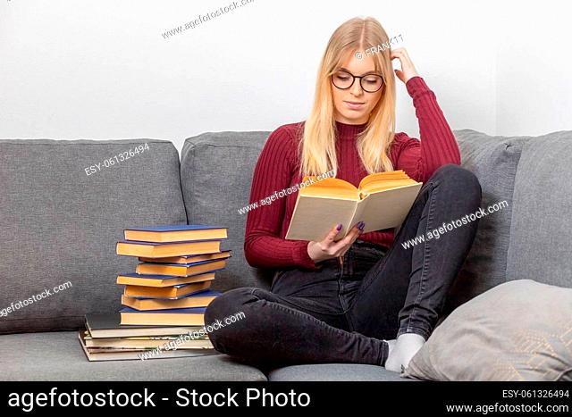 Young woman is sitting on the couch and reading a book. Self education concept