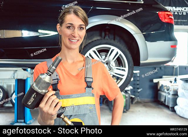 Portrait of a beautiful and confident woman holding an impact wrench while working as auto mechanic in a modern automobile repair shop with tuning services