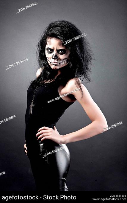 Young woman in day of the dead mask skull face art. Halloween face art with fog on black background