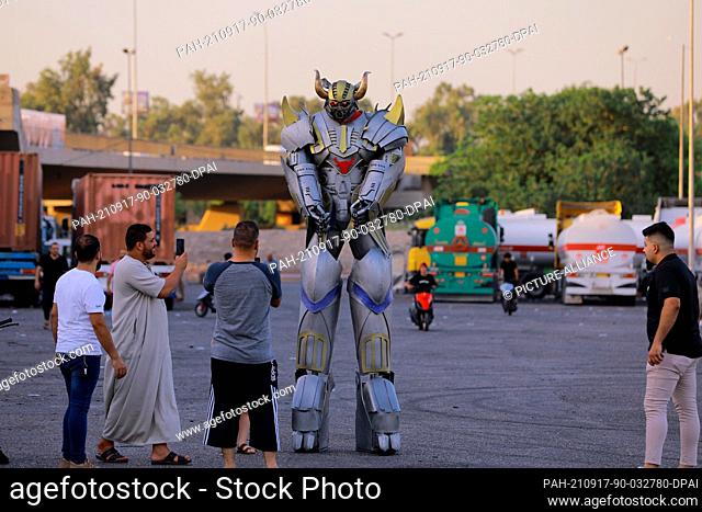17 September 2021, Iraq, Baghdad: A robot suit with a man inside designed by Ali Maytham Al-Zubaidi (L), 22 years, to entertain people inside malls and markets